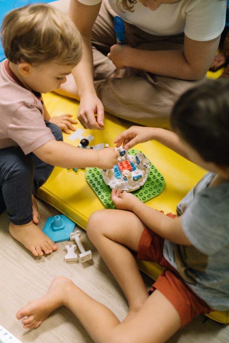 2 boys playing with duplo on the ground