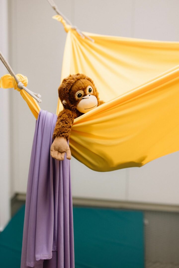 Toy monkey relaxing in yellow swing