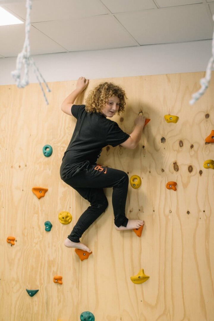 Boy at the top of a rock climbing wall