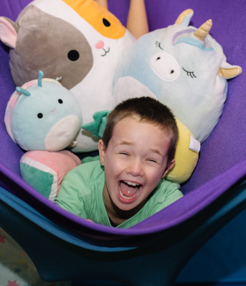 Boy in a stretchy sensory swing with squishmallows